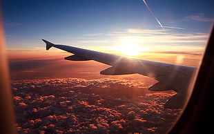 clear glass airplane window showing sunset with cloudy sky