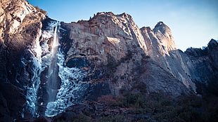 rock mountain with falls under blue sky HD wallpaper