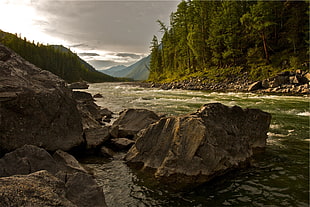 rock formation near river under white clouds during daytime