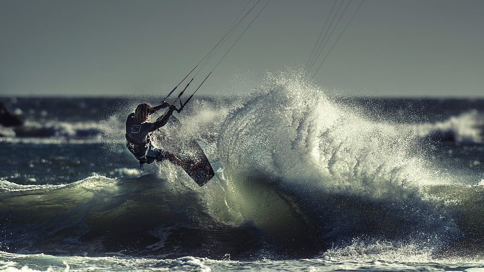 man hanging on rope on wave body of water photo HD wallpaper