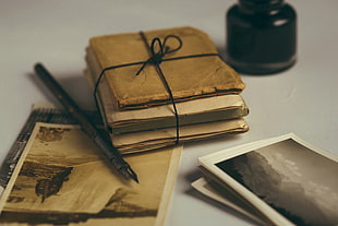 pile of books tied of black rope beside fountain pen