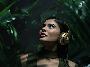 woman in green turtle neck top wearing gold beats headphones