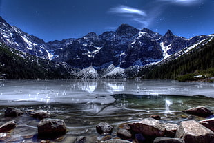 body of water near mountains during nighttime HD wallpaper