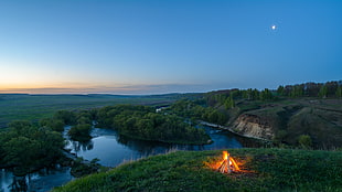 bonfire on green grass field overlooking body of water