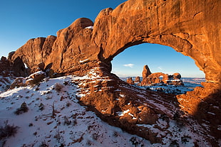photo of brown arch mountain near ocean during day time HD wallpaper