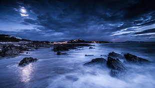 landscape photography of rocky seaside under cloudy sky during nighttime HD wallpaper