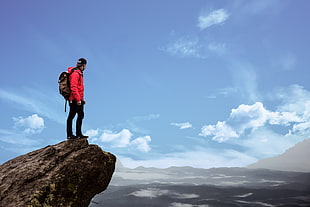 man standing in at the tip of the mountain