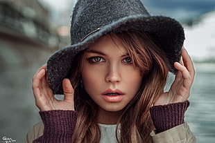 woman wearing gray hat and sweatshirt standing near body of water