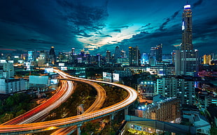 time lapse photo of city buildings under blue sky and gray clouds HD wallpaper