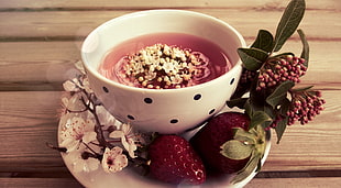 white ceramic bowl and two red strawberries