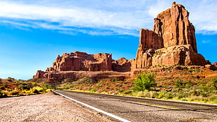 empty concrete road near rock formation HD wallpaper