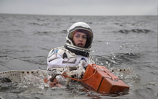 woman astronaut on body of water while holding orange case front the Martian movie still HD wallpaper