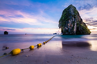 rock formation on body of water during daytime