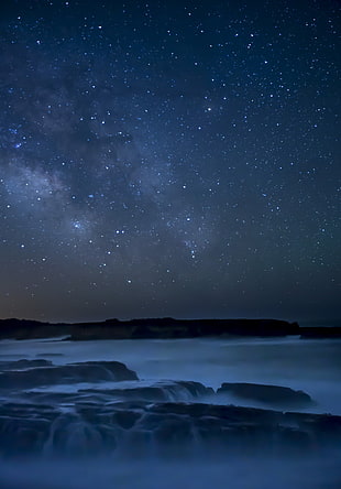 body of water and rock under dark sky during night time HD wallpaper