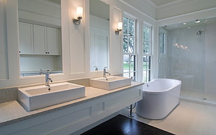 photo of white wooden sink with mirrors beside freestanding bathtub HD wallpaper