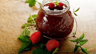 still life photography of strawberry jam beside two strawberries