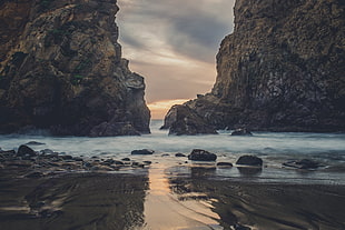 beach shore with a view of two cliffs under brown sky