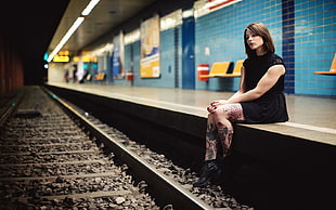 woman in black sleeveless dress sitting beside train railway HD wallpaper