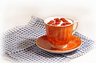 white and orange ceramic teacup and saucer