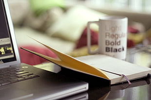 selective focus photography of black and white hardbound book near black laptop computer \