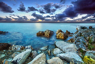 rock formation near body of water during sunset