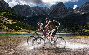 two man and woman riding on bike near mountains HD wallpaper
