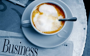 white ceramic cappuccino with foam in white ceramic teacup with saucer