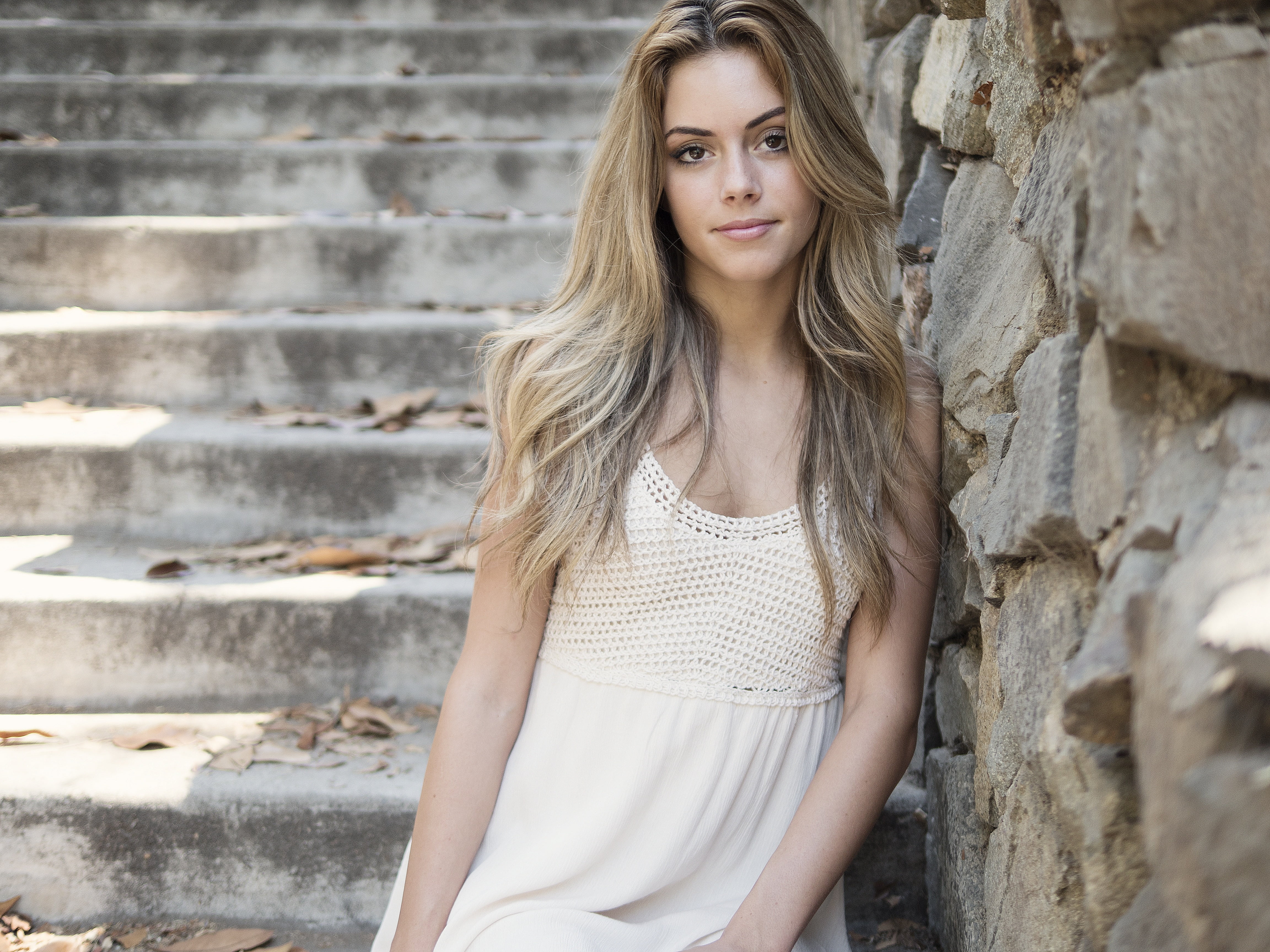 woman in white scoop-neck shirt standing near brown concrete wall during daytime