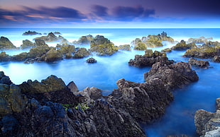 rock formation on body of water under blue sky during daytime HD wallpaper