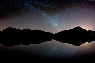 silhouette of two mountain near sea at night time