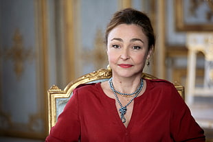 woman wears red split-neck long-sleeved top sits on brown chair HD wallpaper