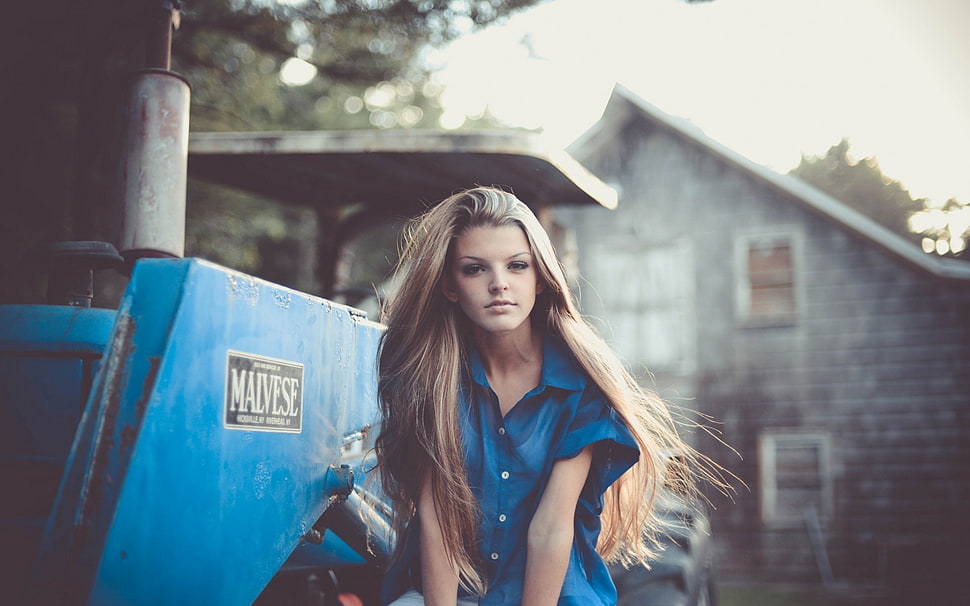 woman wearing blue button-up shirt standing near the tractor HD wallpaper