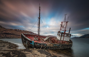 broken sailing ship on beach shore with a view of mountains under blue sky HD wallpaper