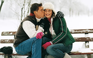 man kissing woman near brown wooden bench