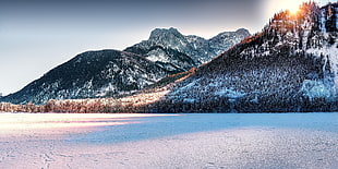 brown and white mountain covered by snow under sunset