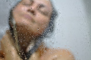woman taking a bath behind clear glass shower stall with water dews HD wallpaper