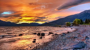 sunset behind the mountain beside body of water HD wallpaper