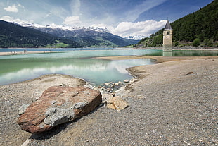 gray stone near river surround by mountains under blue sky