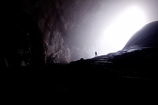 person in the entrance of cave HD wallpaper