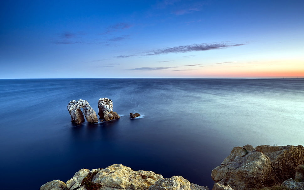 photography of arch-shaped rock on body of water during golden hour HD wallpaper