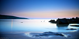 photography of seashore near rocks during golden hour HD wallpaper