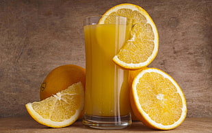 clear highball glass with orange juice and sliced orange citrus