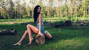 woman wearing gray sleeveless shirt sitting on wood log near forest HD wallpaper