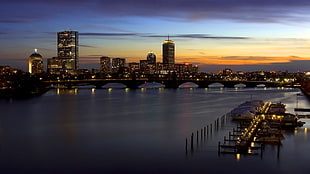 silhouette of bridge near lightened high rise buildings during sunset