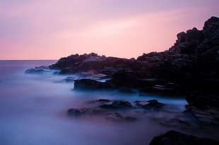 black rock formation covered with fog