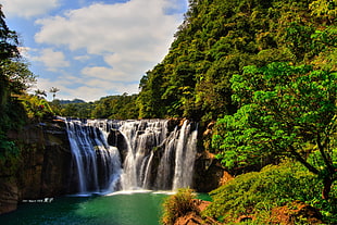 time lapse photography of waterfalls beside trees during daytime