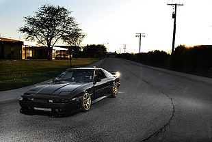 black coupe on the road during sun set