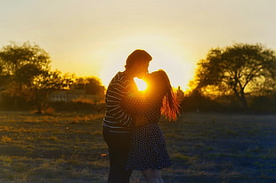 man and woman kissing during golden hour