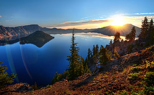 brown mountain beside body of water during sunset