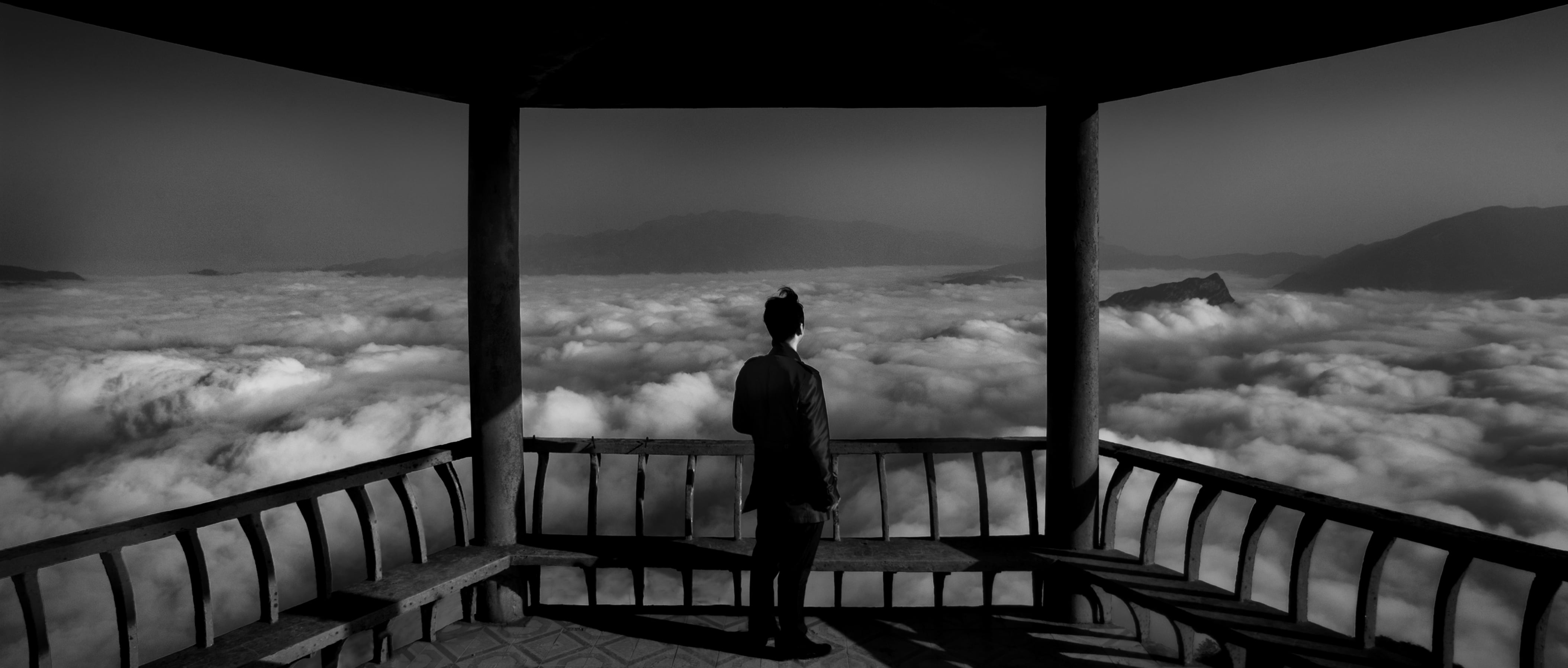 grayscale photo of person standing near bench